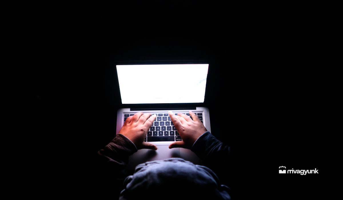 hacker ül a sötétben, felülről kinyitott laptoppal