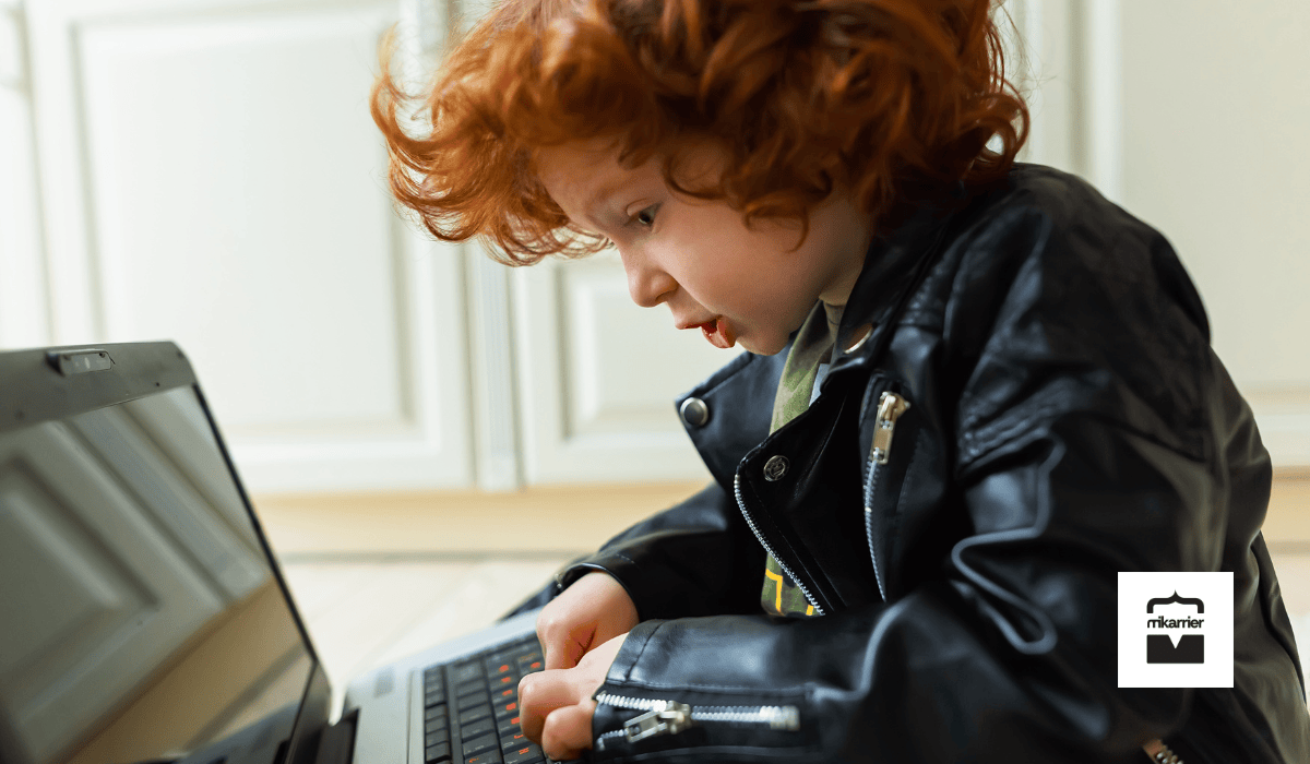 Kíváncsi kisgyerek laptop előtt ül és a billentyűzetet figyeli, a pályakezdők, junior munka és MI által átalakított tanulási utak témájához.