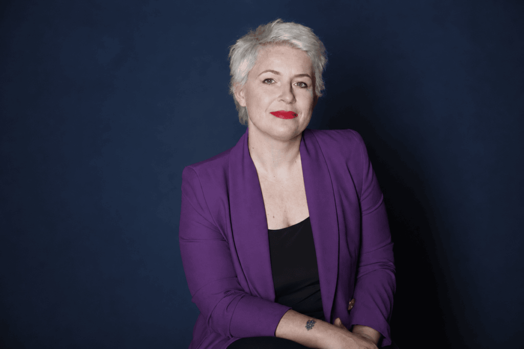dr. Stier Kata lila blézerben ül sötét háttér előtt, professzionális portréfotón.