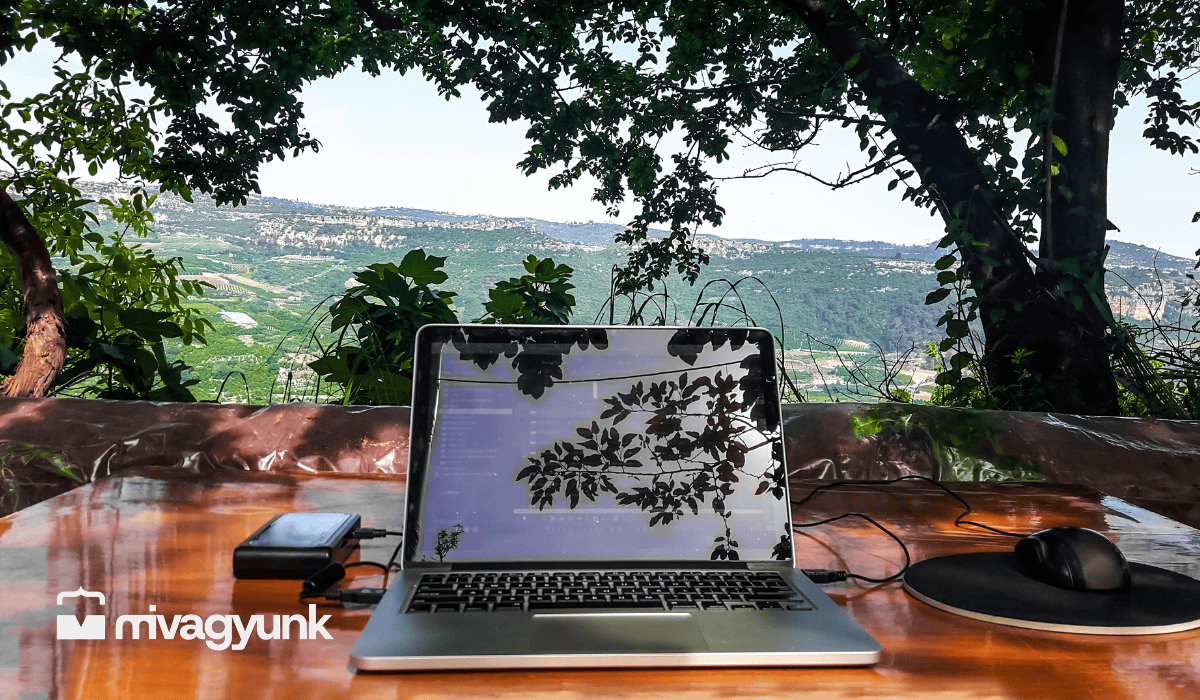 Nyitott laptop egy teraszon, zöld hegyvidéki panorámával a háttérben, szabadúszó munka és MI-használat témájú cikkhez.